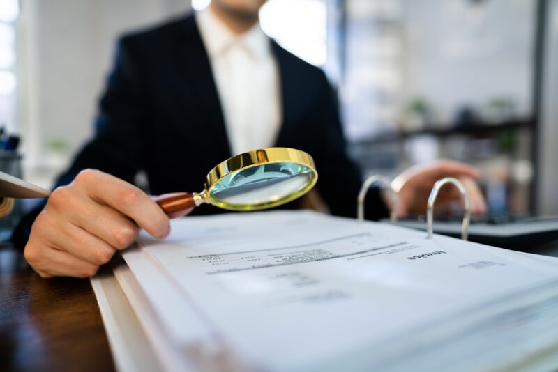 Valuer examining proprety valuation documents with a magnifying glass, highlighting the importance of detailed scrutiny and accuracy in property valuations for SMSFs.
